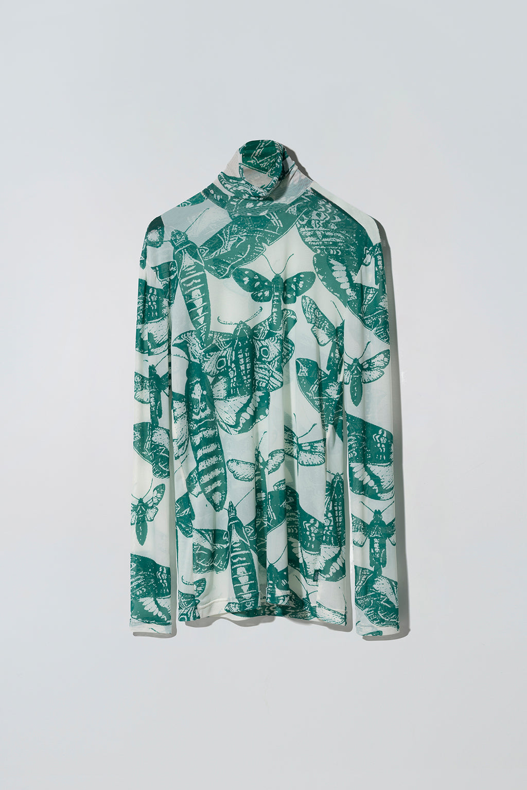 Green and white butterfly patterned long sleeve top on a white background