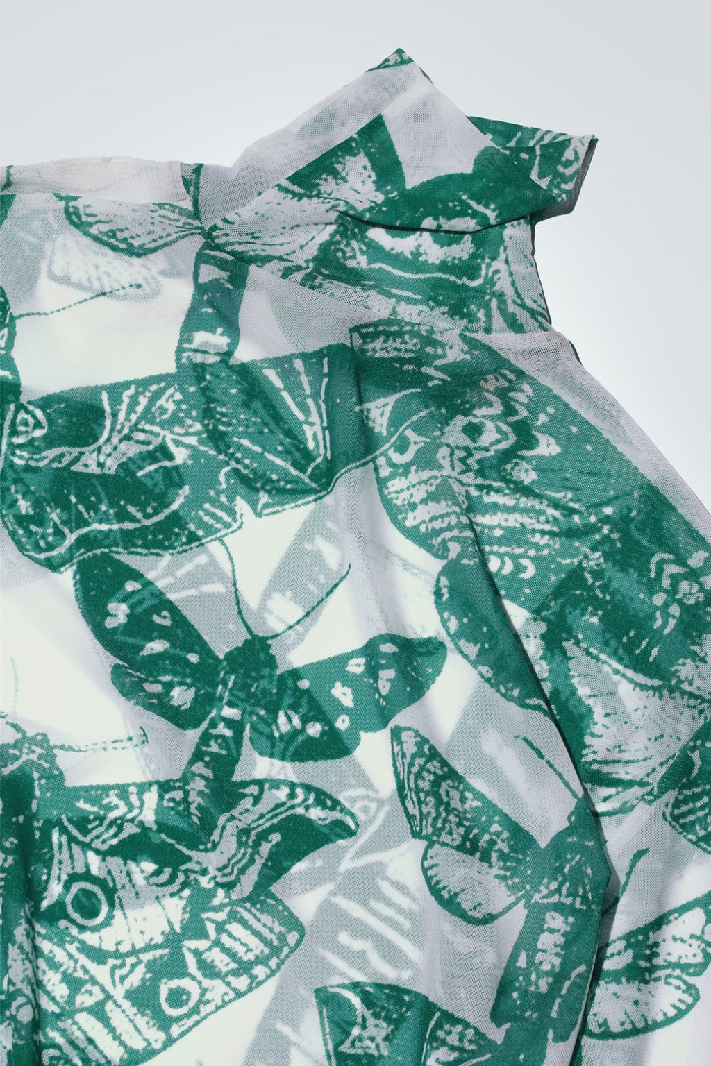 Green and white butterfly patterned top on a white background