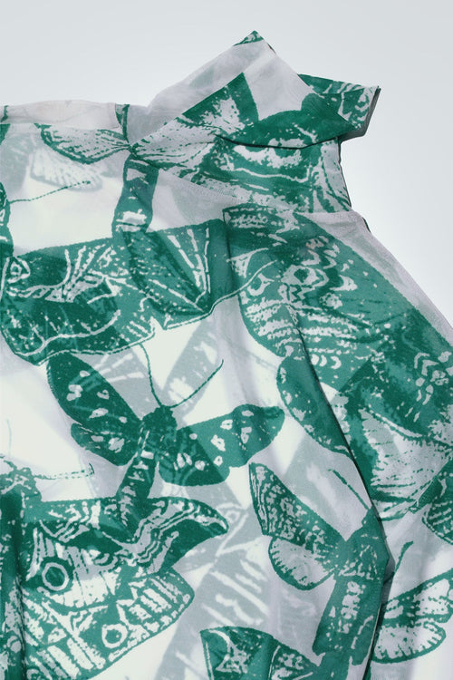 Green and white butterfly patterned top on a white background