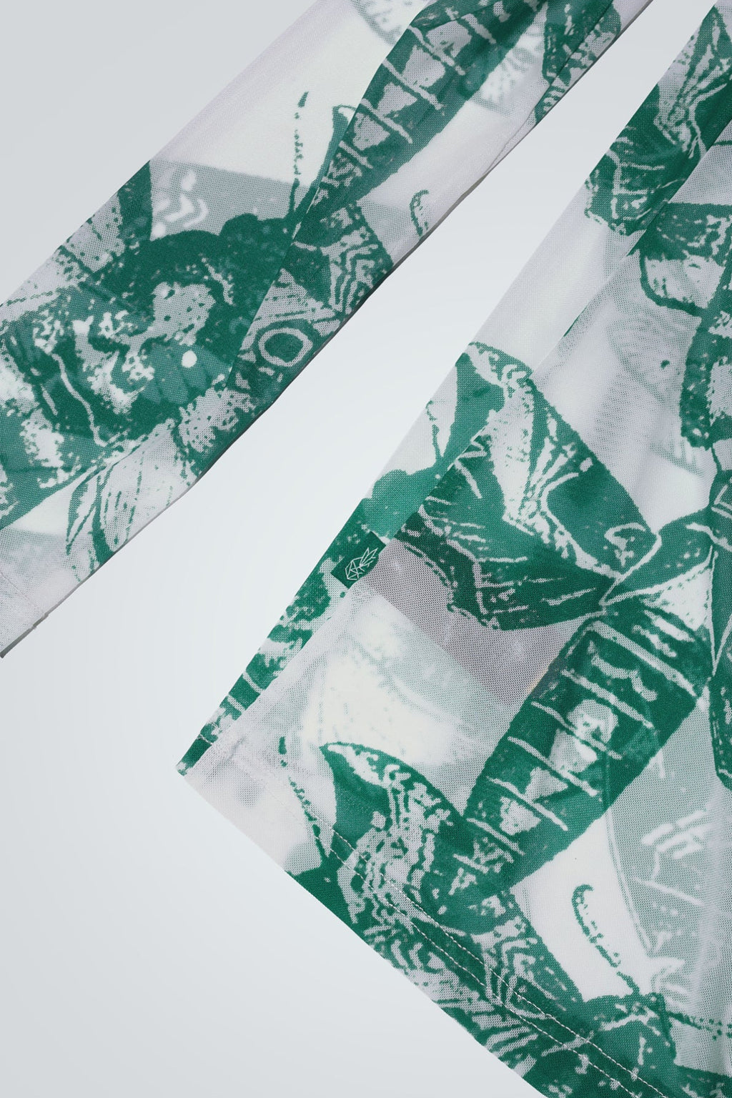 Close-up of green and white butterfly patterned top on a white background