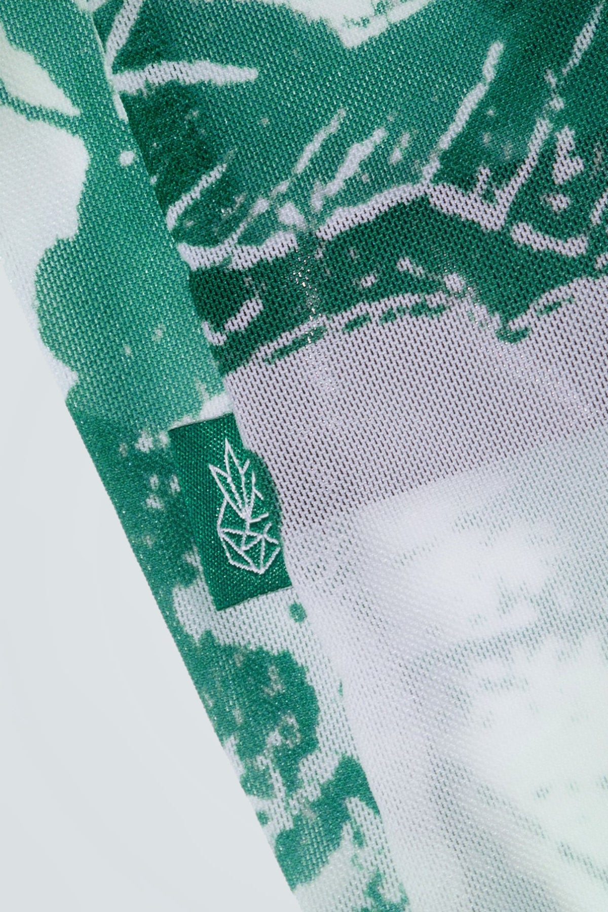 Close-up of green and white patterned fabric with a logo on a white background