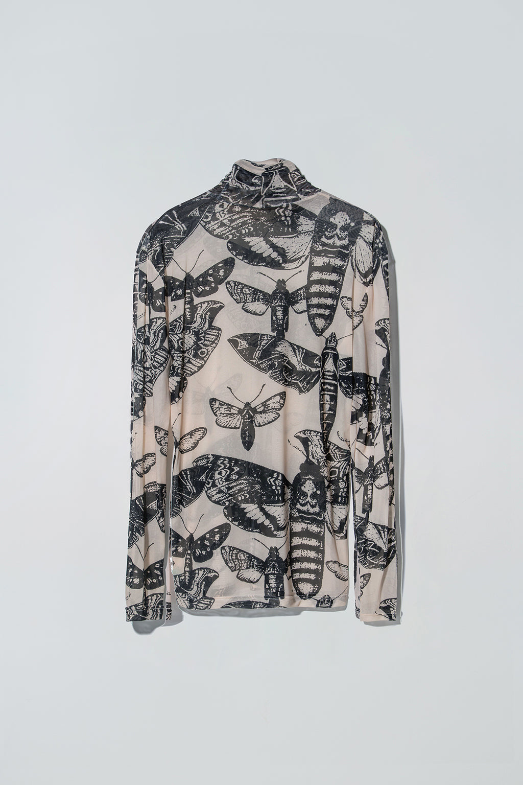 Black and nude butterfly patterned long sleeve top on a white background