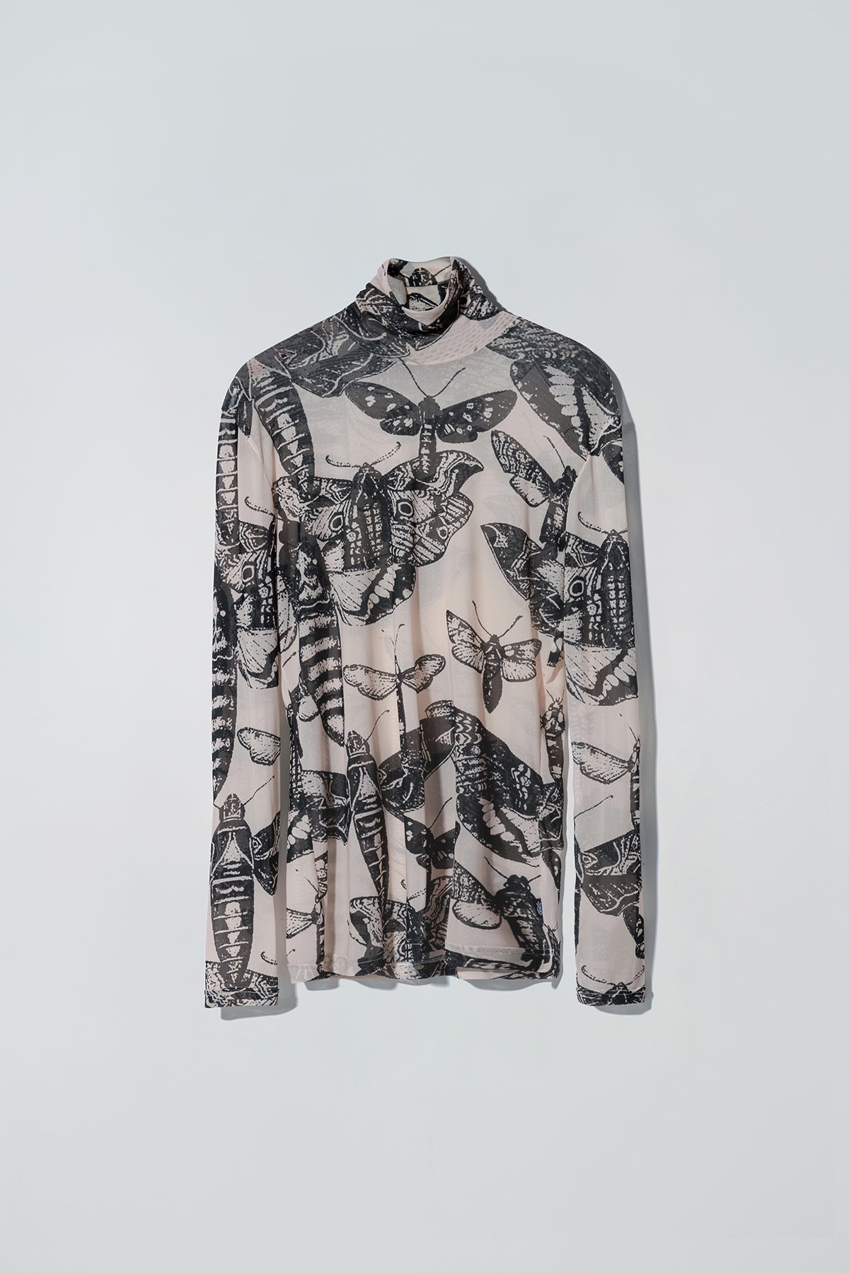 Black and nude butterfly patterned long sleeve top on a white background