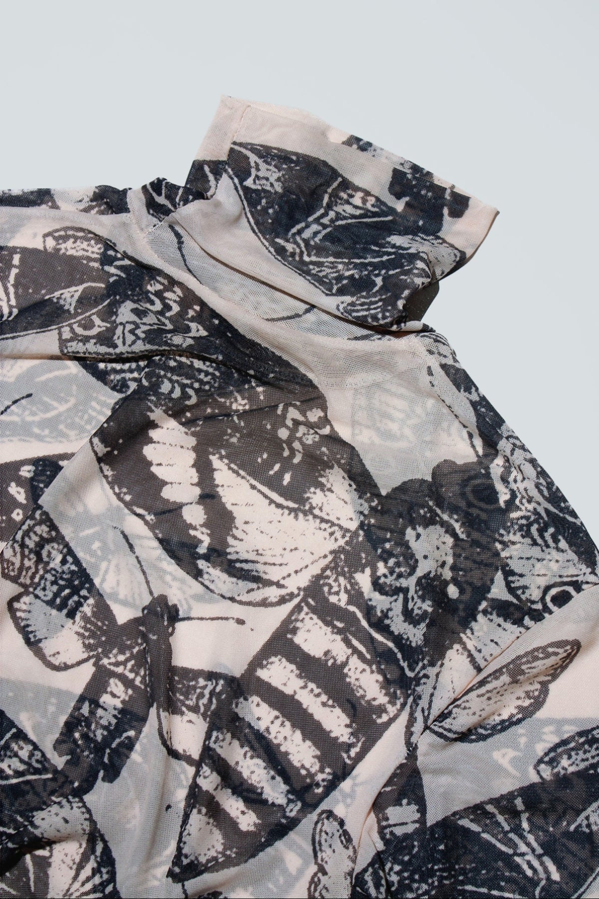 Black and nude butterfly patterned top on a white background