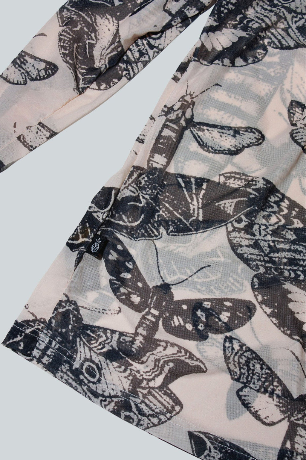Close-up of black and nude butterfly patterned top on a white background