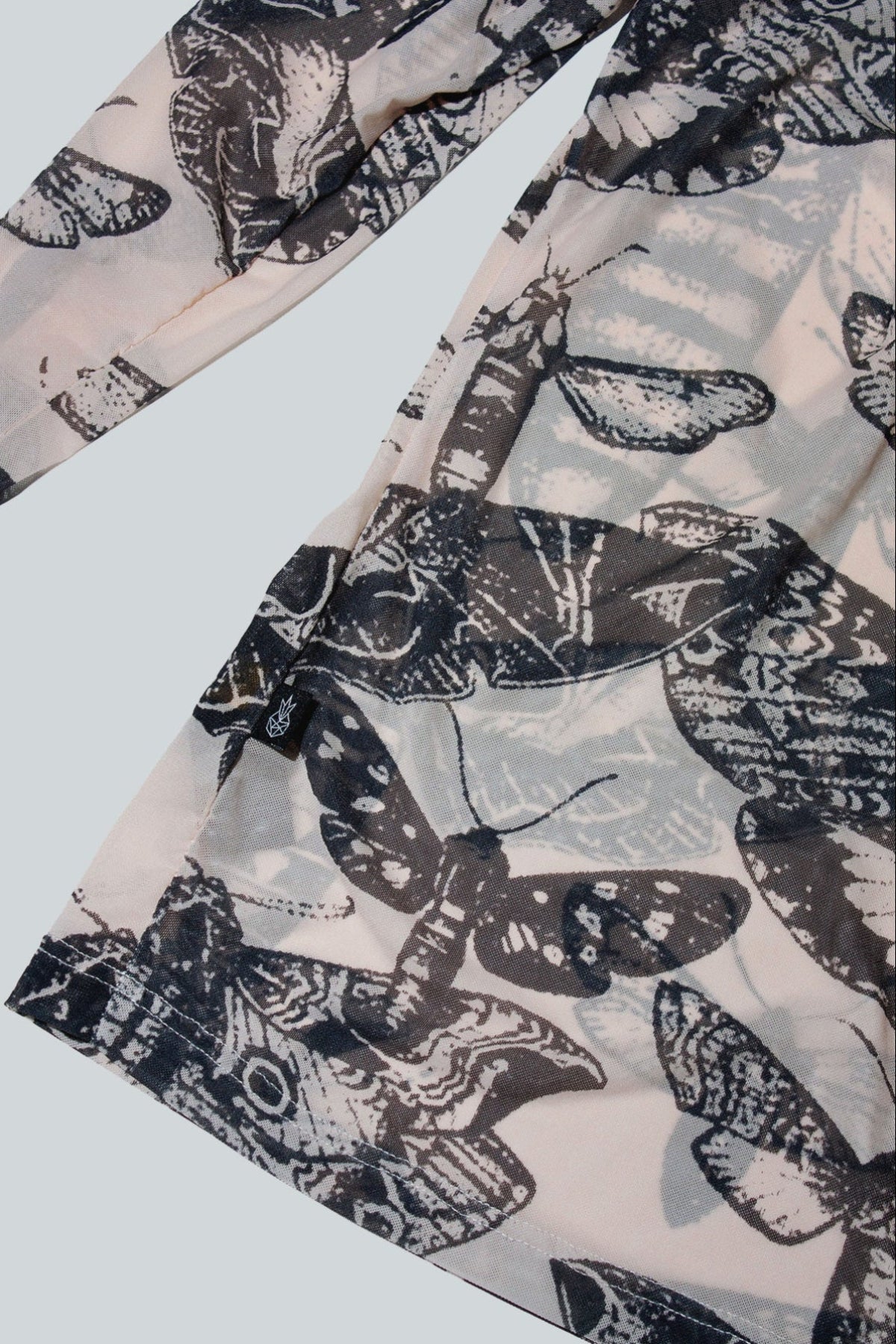 Close-up of black and nude butterfly patterned top on a white background