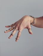 Hand wearing multiple gold and silver rings on a plain background