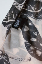 Close-up of black and nude patterned fabric with a logo on a white background