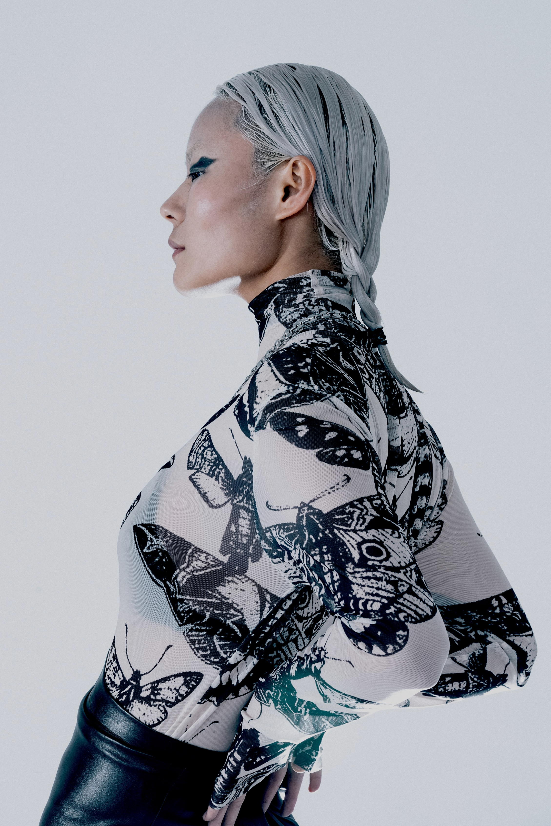 Model wearing a black and nude butterfly patterned long sleeve top