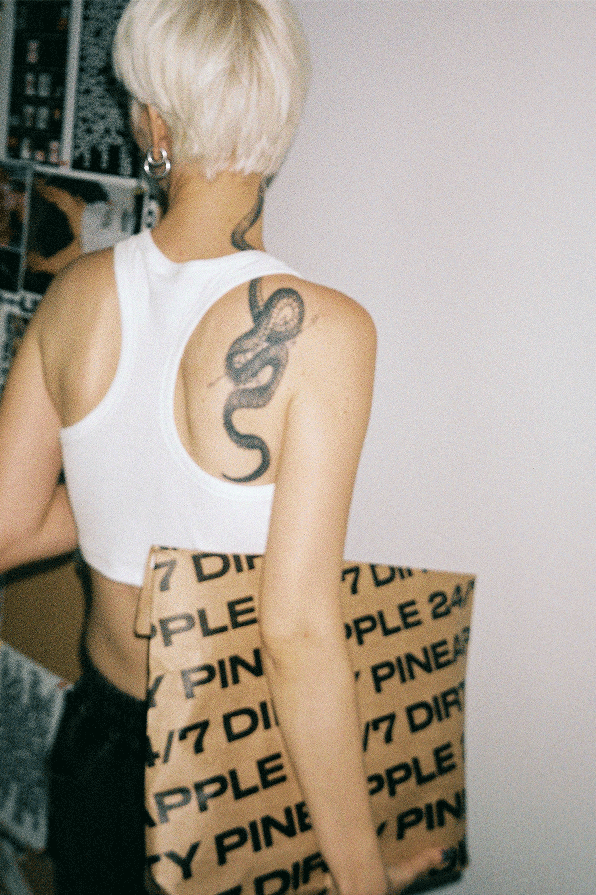 Person wearing a white tank top with a  standing against a plain background