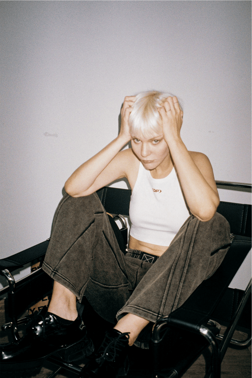 Person wearing a white tank top with a logo, standing against a plain background