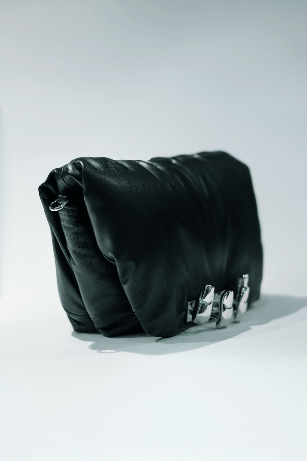 Black leather handbag with a hand silver hardware grip on a white background