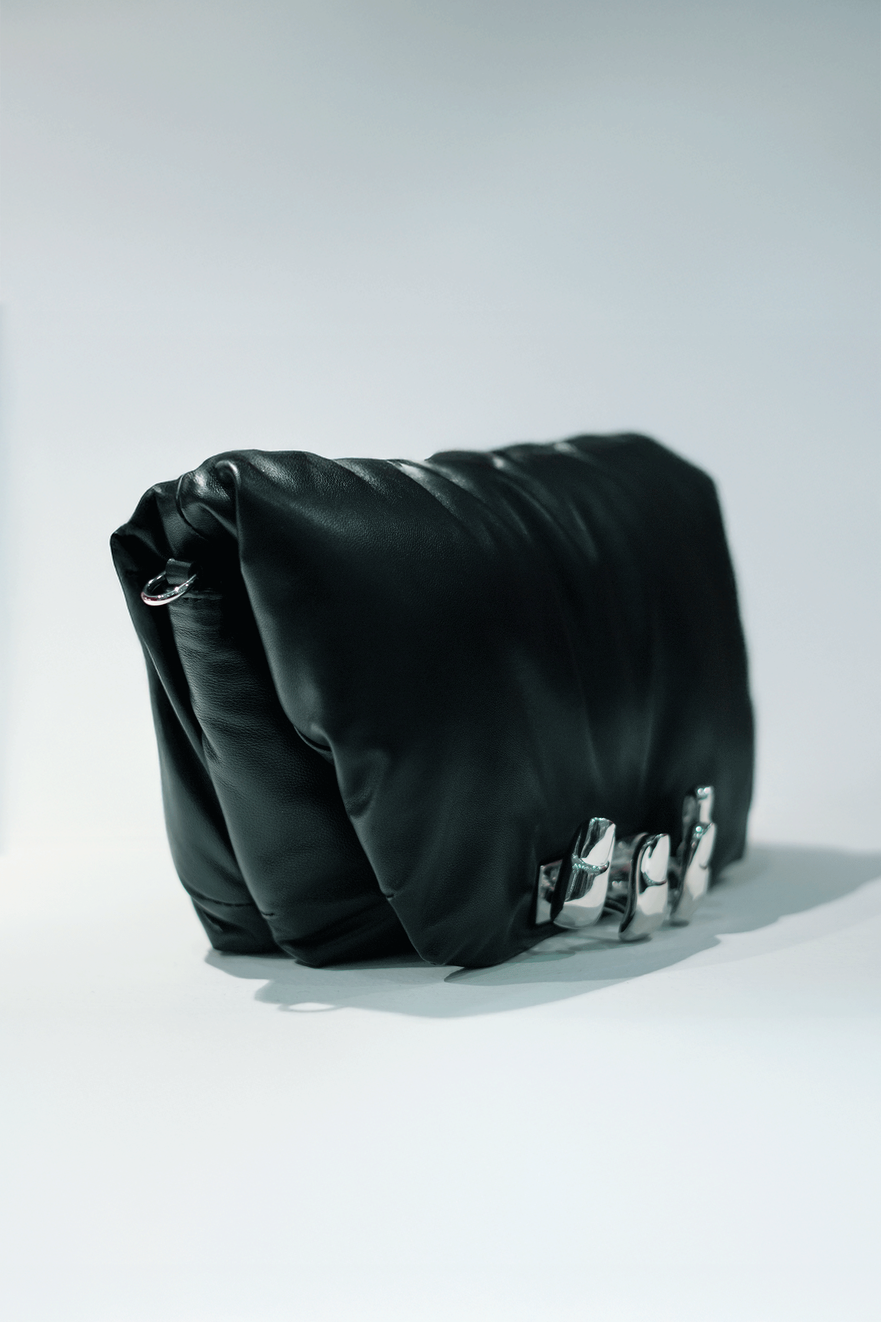 Black leather handbag with a hand silver hardware grip on a white background