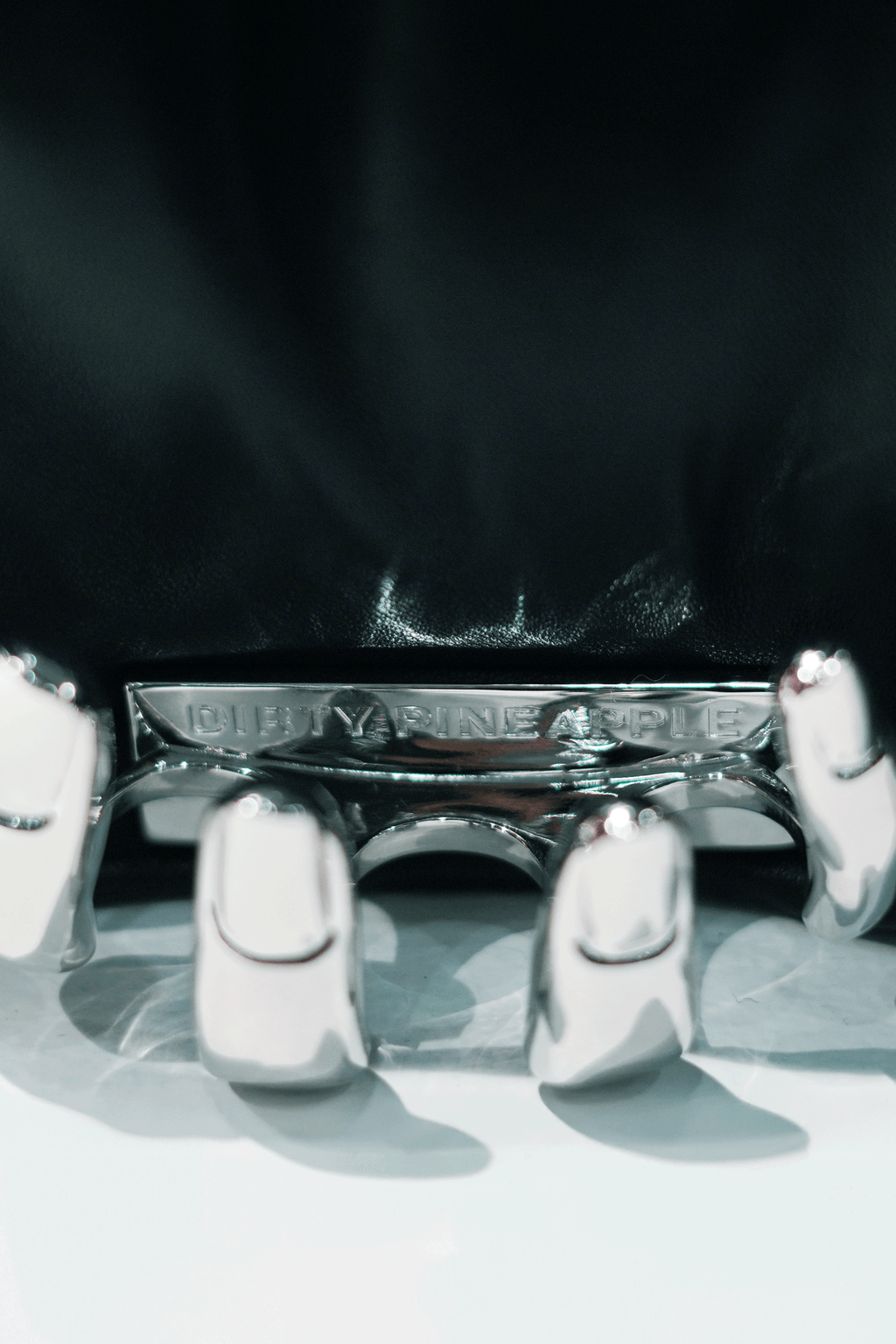 Close-up of a black handbag with a visible Dirty Pineapple brand name on a white background