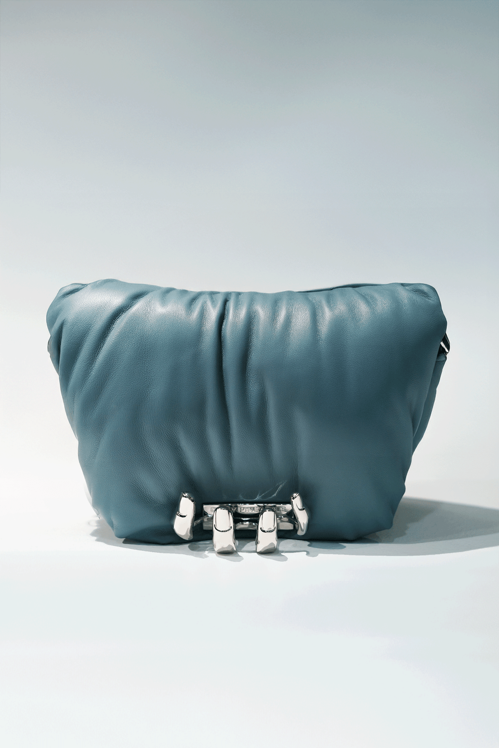 Blue leather handbag with a hand silver hardware grip on a white background