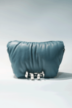 Blue leather handbag with a hand silver hardware grip on a white background