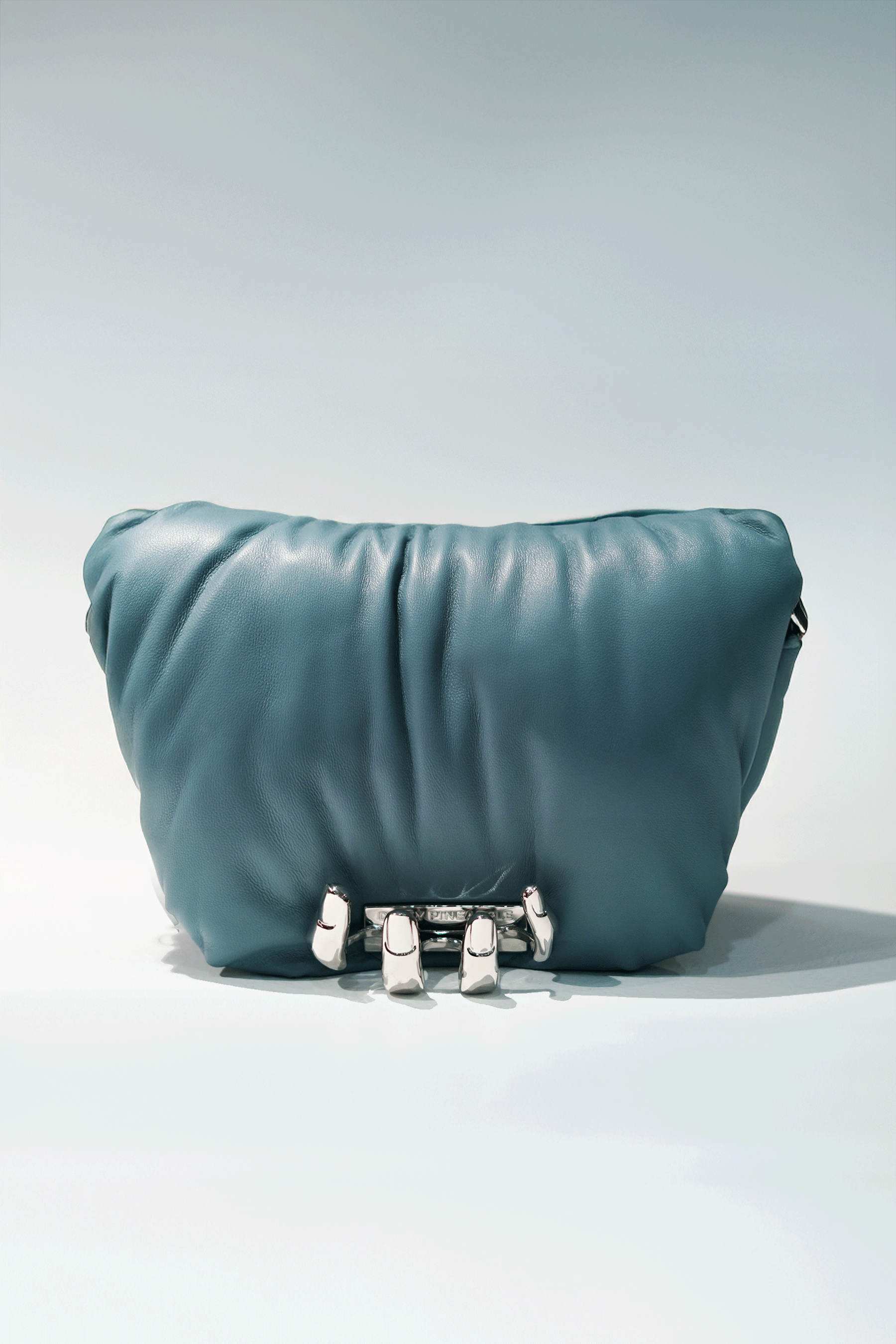 Blue leather handbag with a hand silver hardware grip on a white background