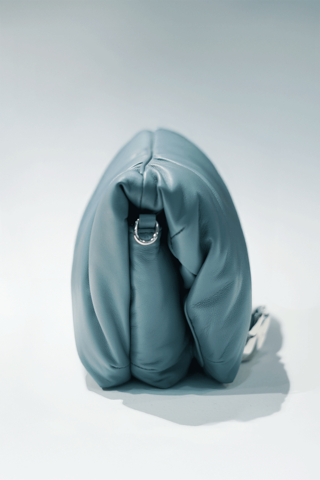 Blue leather handbag with a hand silver hardware grip on a white background