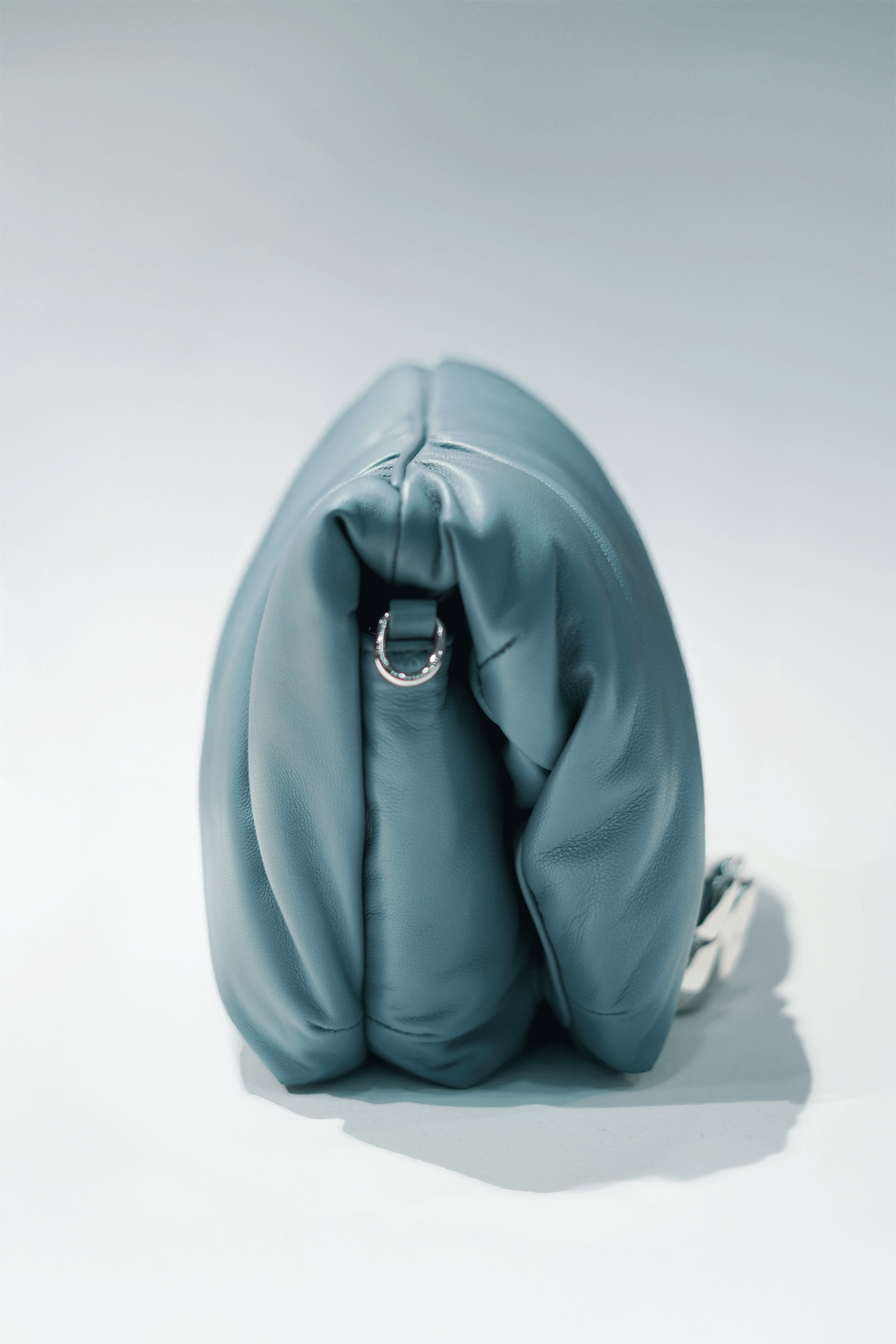 Blue leather handbag with a hand silver hardware grip on a white background