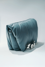 Blue leather handbag with a hand silver hardware grip on a white background