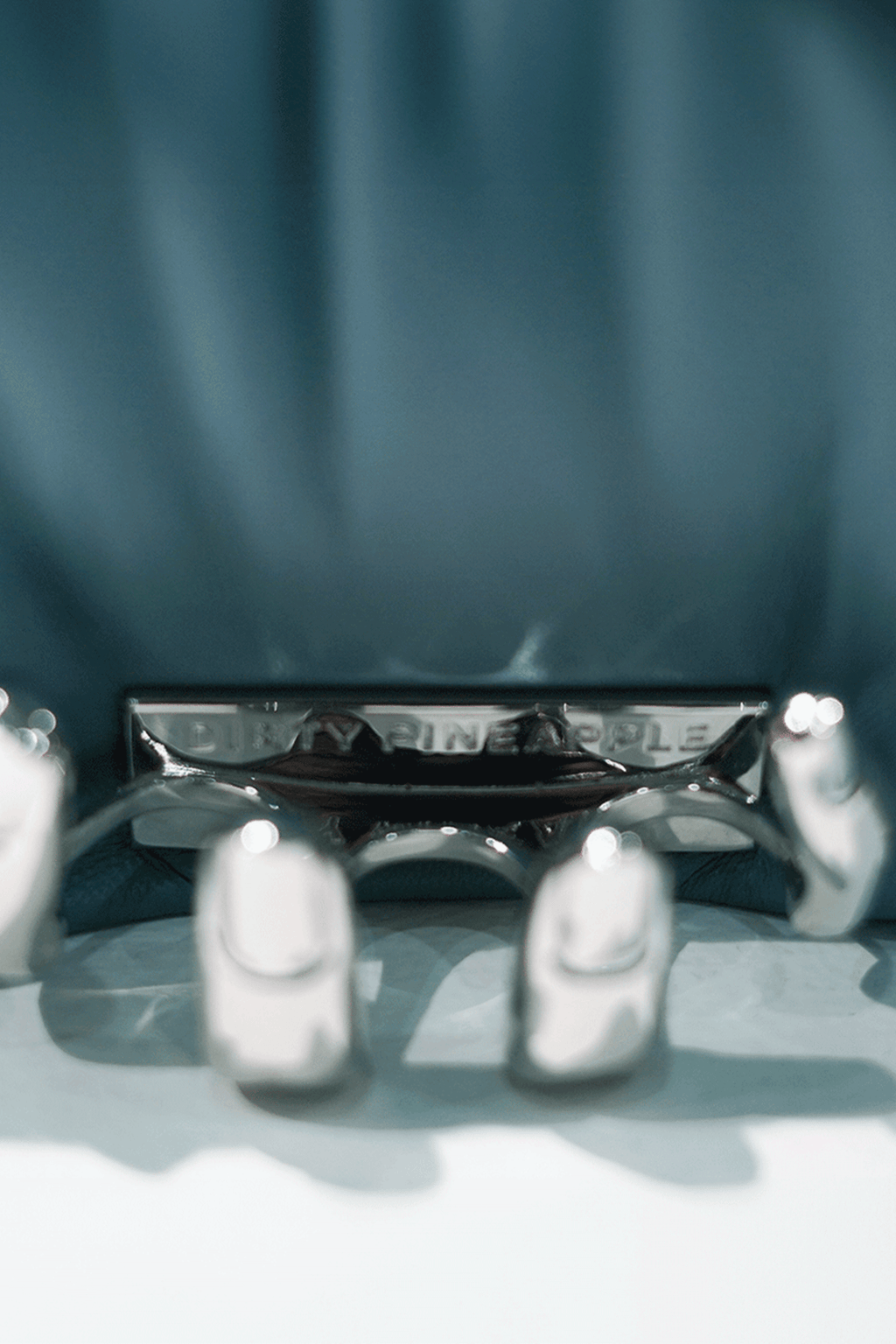 Close-up of a blue handbag with a visible Dirty Pineapple brand name on a white background