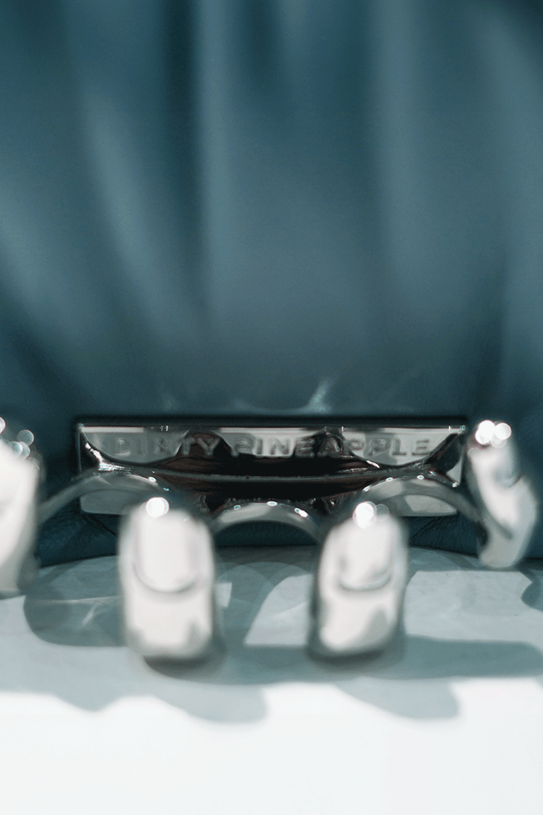 Close-up of a blue handbag with a visible Dirty Pineapple brand name on a white background
