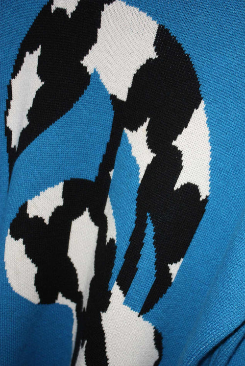 Close up of a blue sweater with a black and white graphic of a fruit cherry