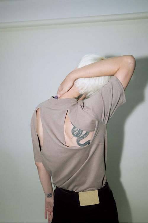 Model wearing a brown slot t-shirt revealing shoulder blade with tattoo