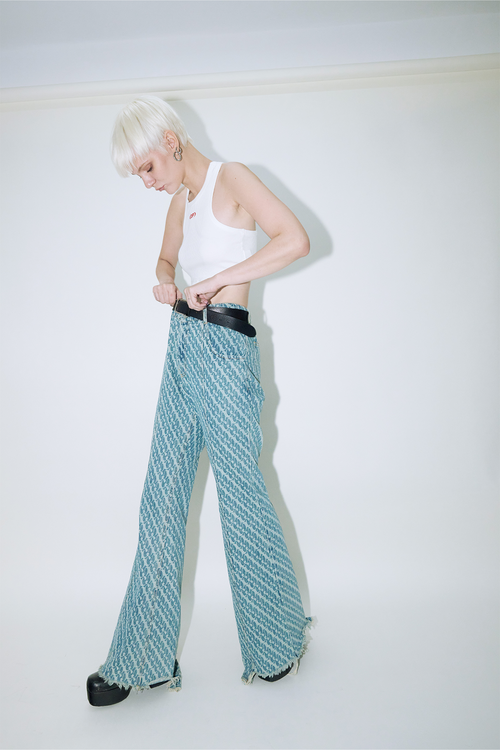 Model wearing Dirty Pineapple signature patterned denim pants flare fit over white background