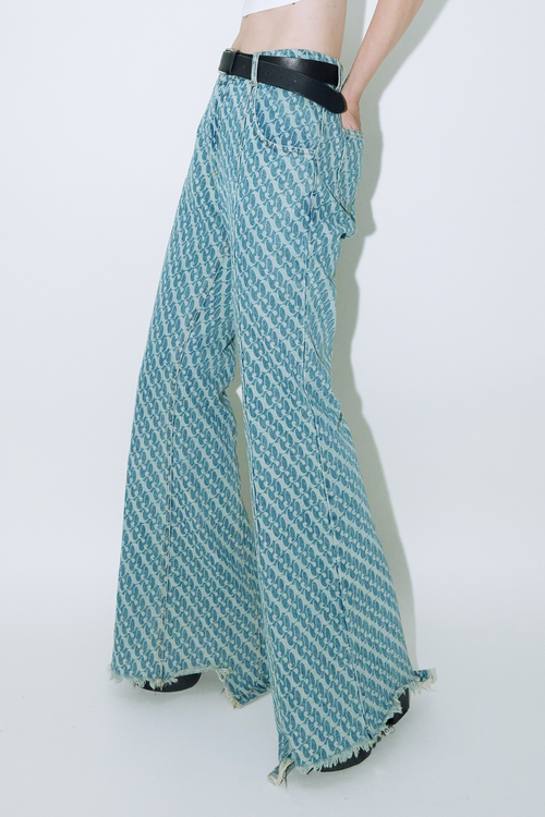 Close up of model wearing Dirty Pineapple signature patterned denim pants flare fit over white background