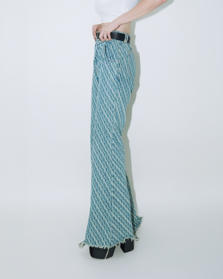 Close up of model wearing Dirty Pineapple signature patterned denim pants flare fit over white background