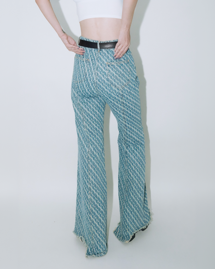 Close up of model wearing Dirty Pineapple signature patterned denim pants flare fit over white background