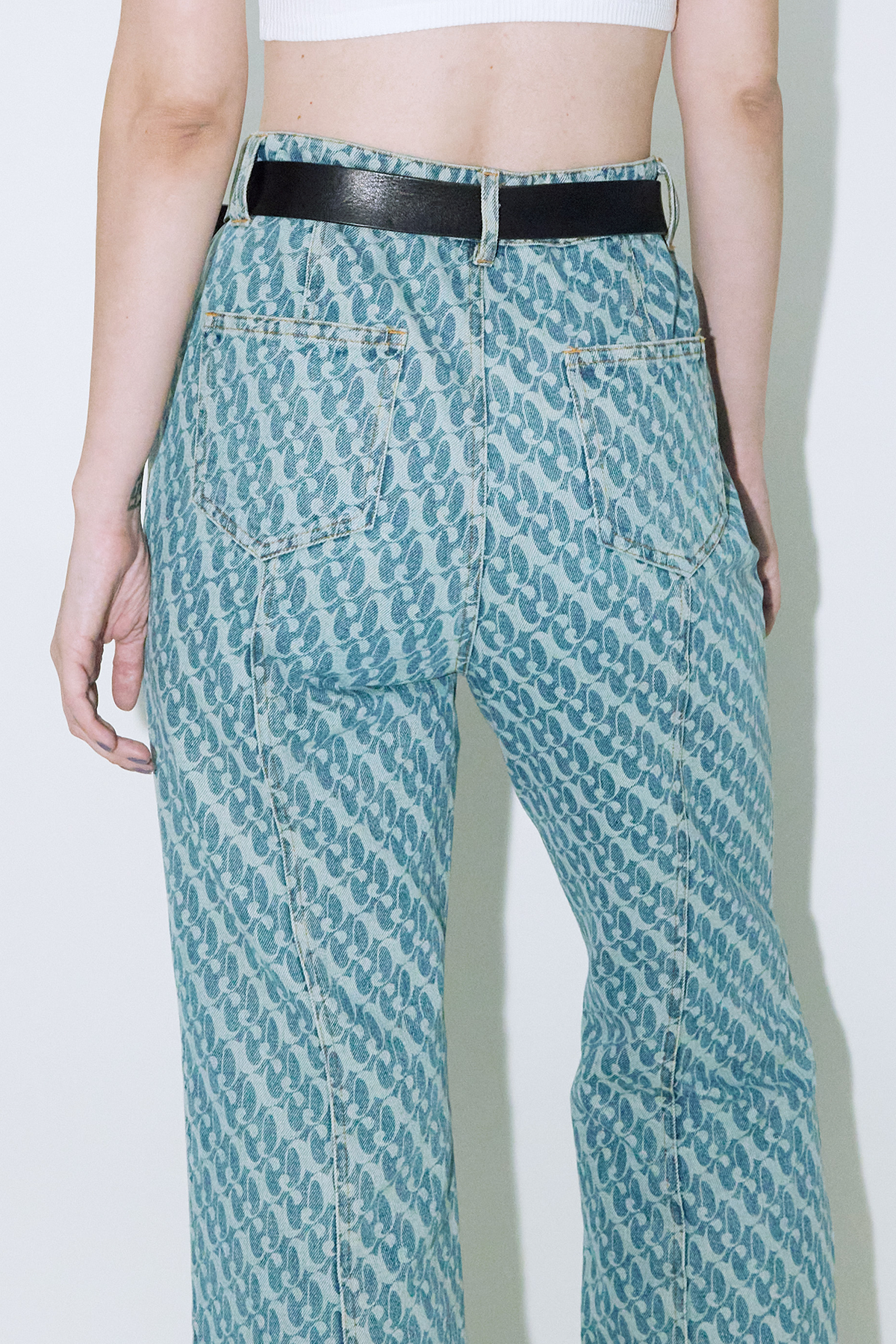 Close up of model wearing Dirty Pineapple signature patterned denim pants flare fit over white background