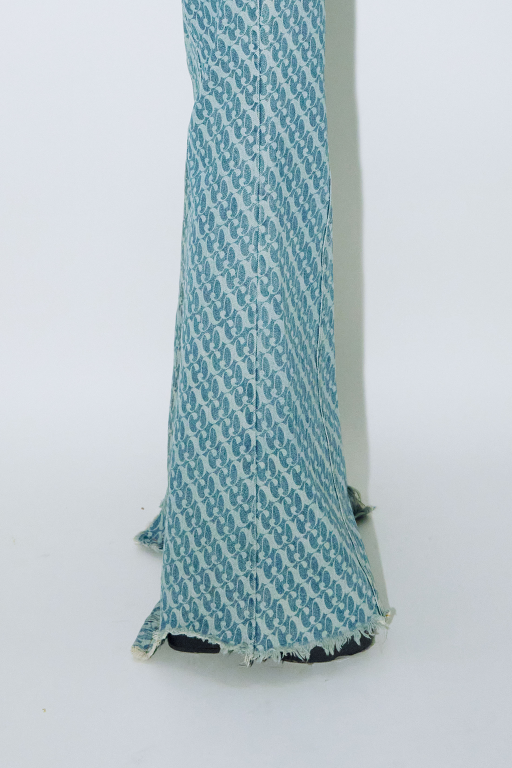 Close up of model wearing Dirty Pineapple signature patterned denim pants flare fit over white background