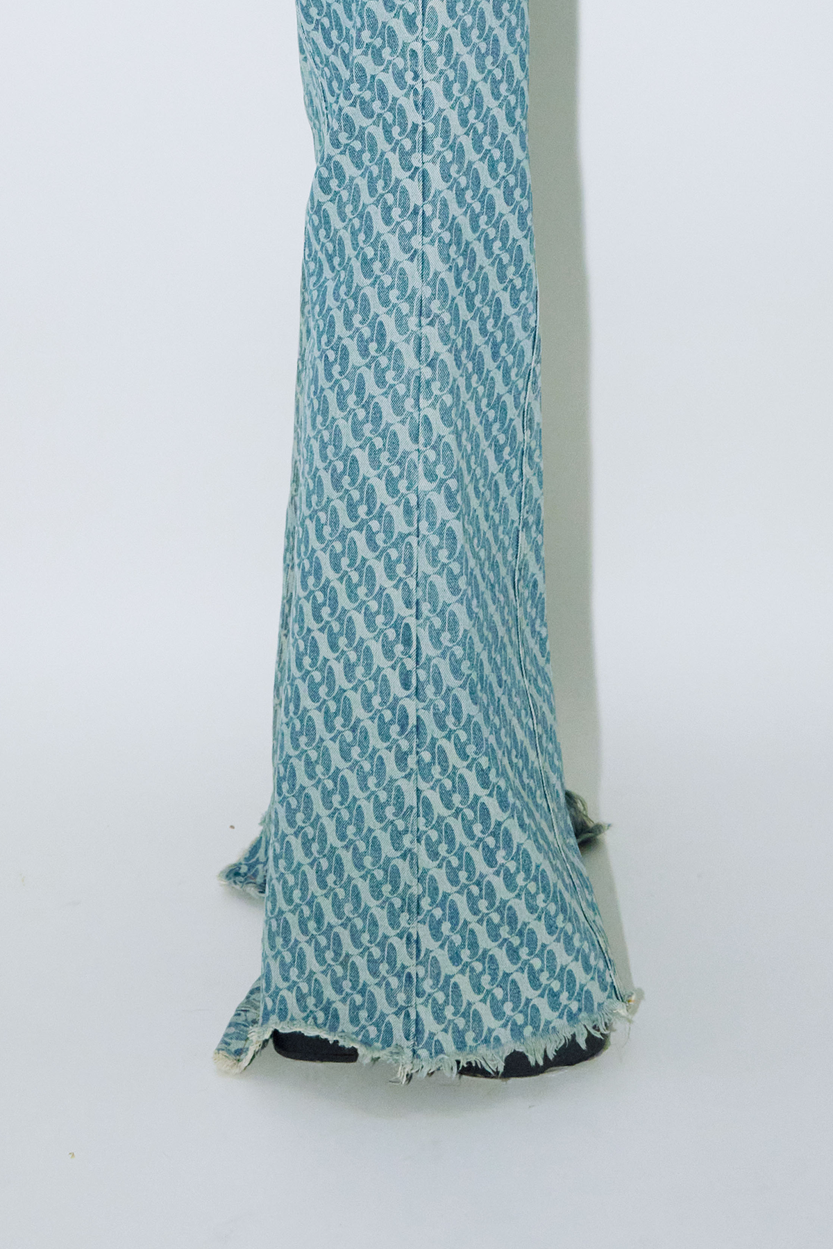 Close up of model wearing Dirty Pineapple signature patterned denim pants flare fit over white background